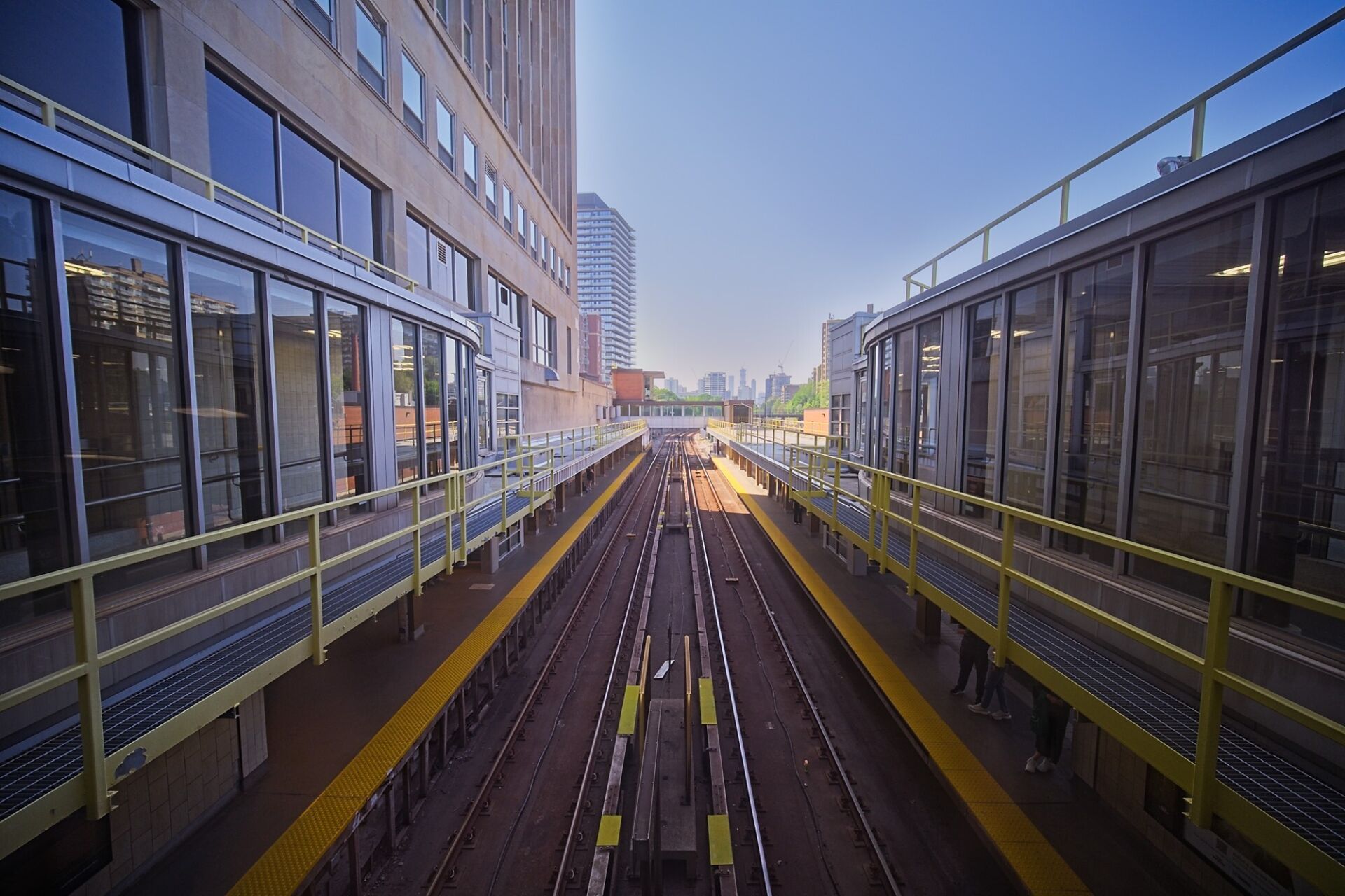 Tracks between buildings with view of the Toronto skyline in the distance.